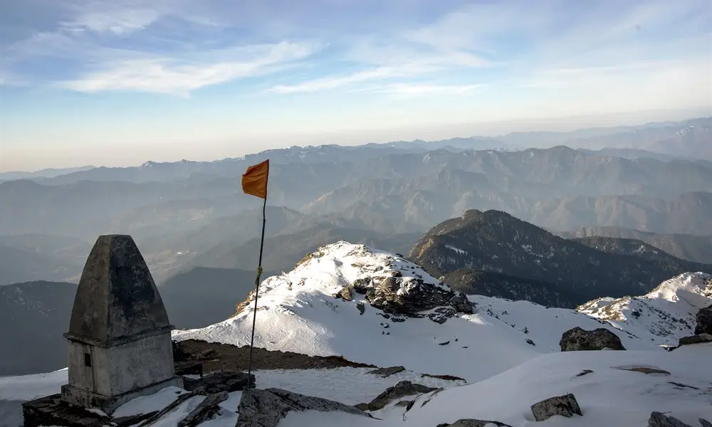 Himalayan trekker on snow summit peak with trekking poles